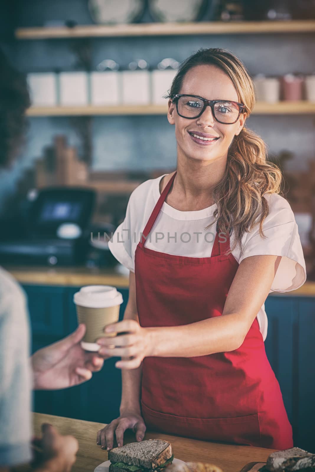 Portrait of waitress serving a coffee to customer at counter in cafÃ©