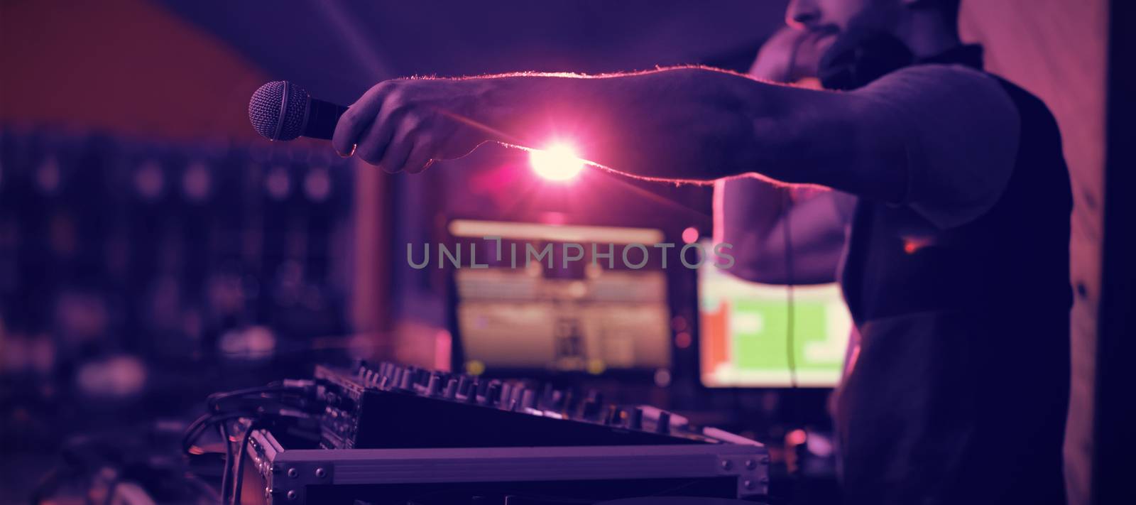 Male dj holding microphone towards the crowd while playing music in bar