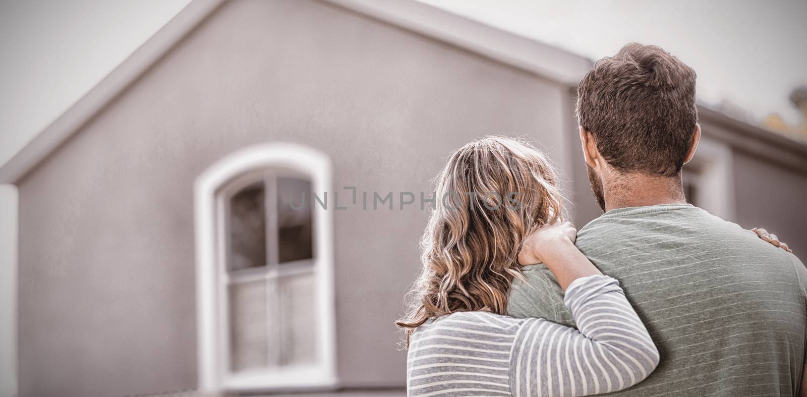 Couple embracing while standing against house
