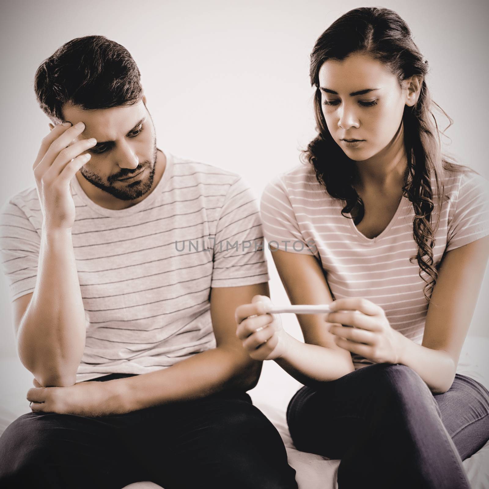 Worried couple finding out results of a pregnancy test in bedroom at home