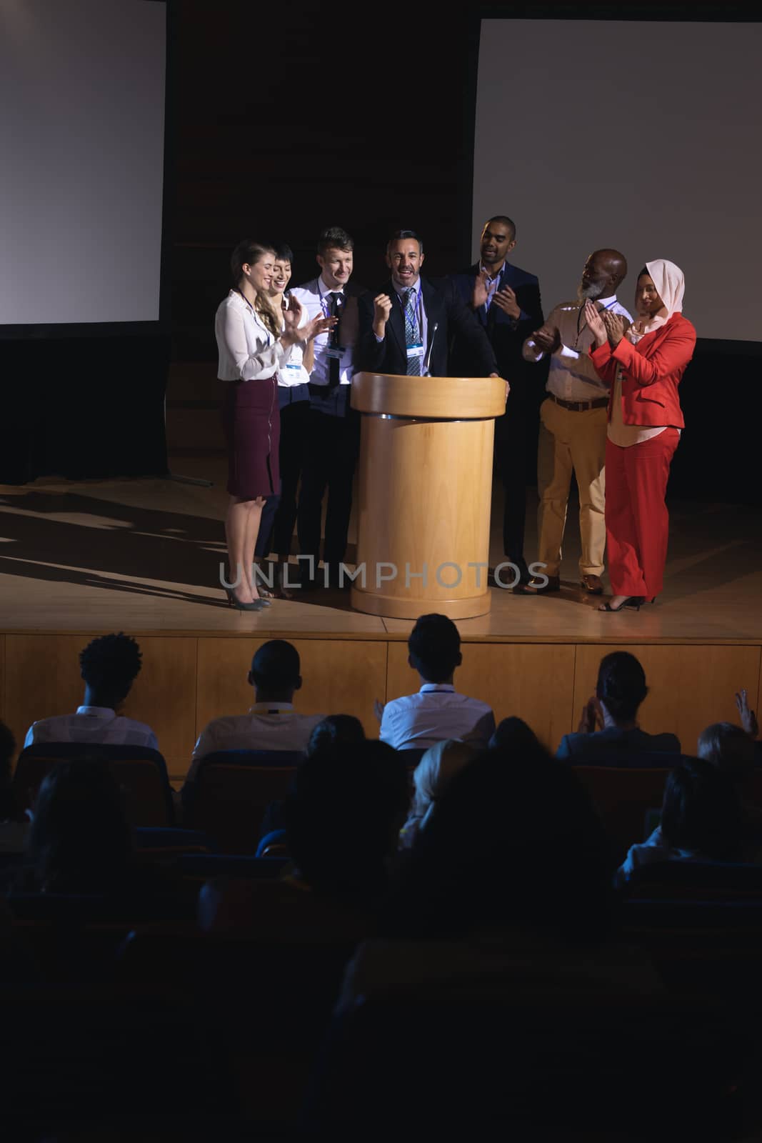 Front view of mixed race business colleagues clapping hand for there colleague  for the success in the auditorium stage in front of the audience