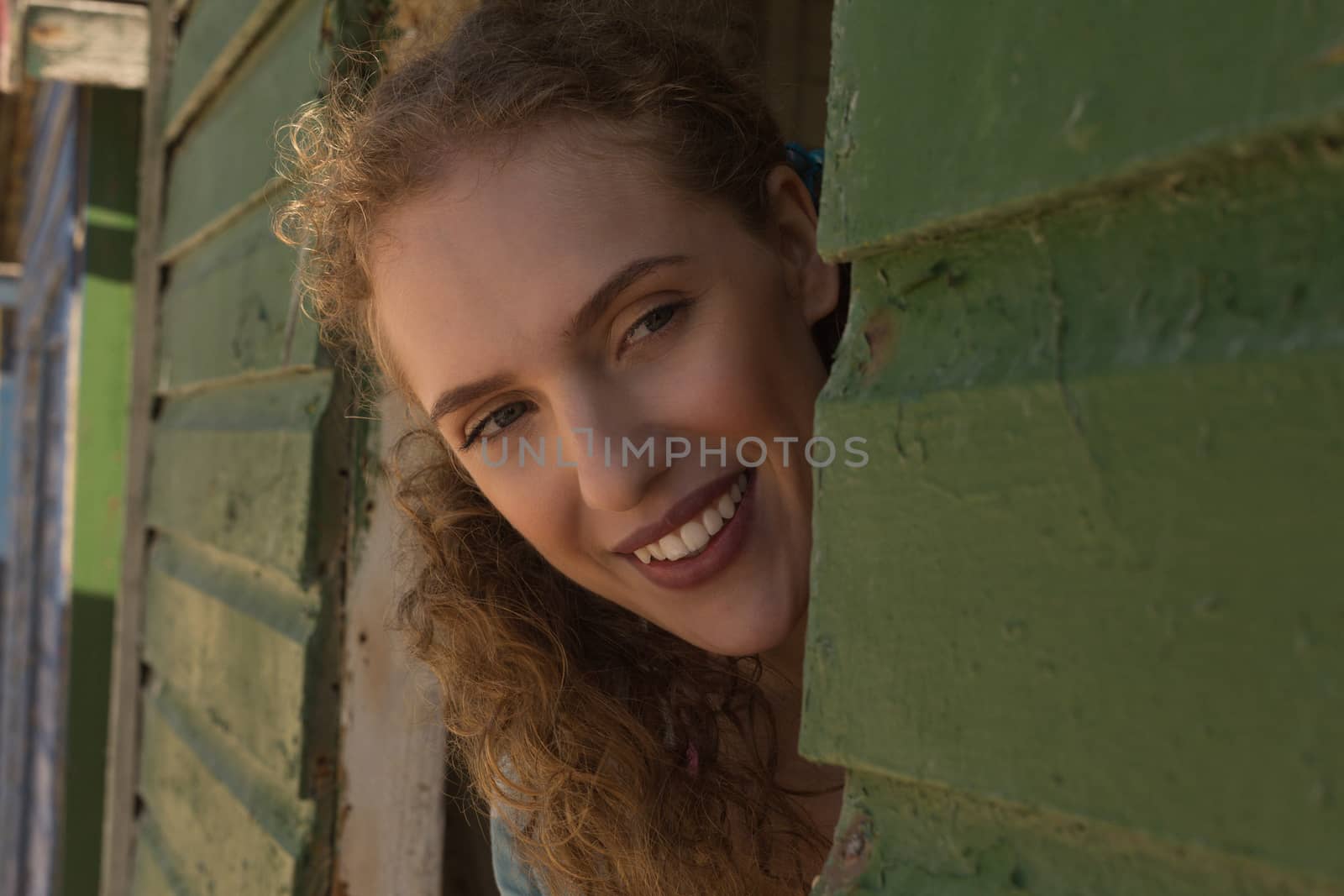 Close-up of happy gorgeous young Caucasian woman looking away from beach hut. She is smiling