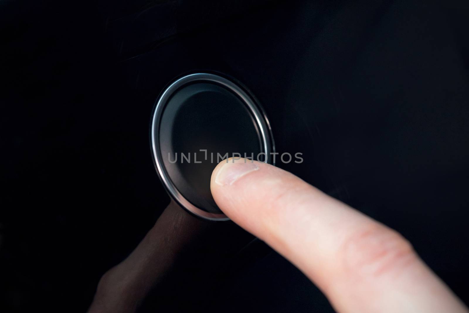 White index finger pressing a small black button 