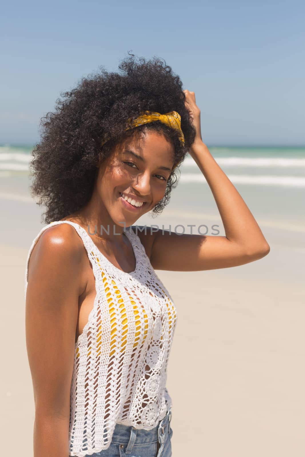 Portrait of happy young African American woman looking at camera standing on the beach. She is smiling