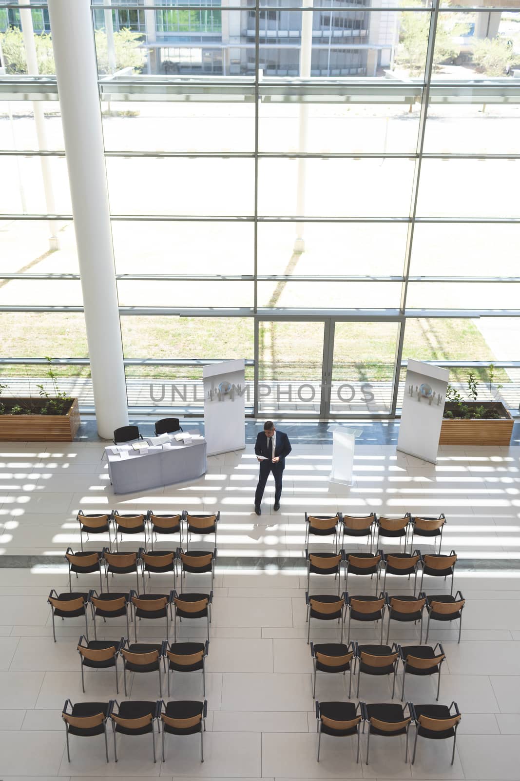 High angle view of well dressed businessman practising speech in empty conference room 