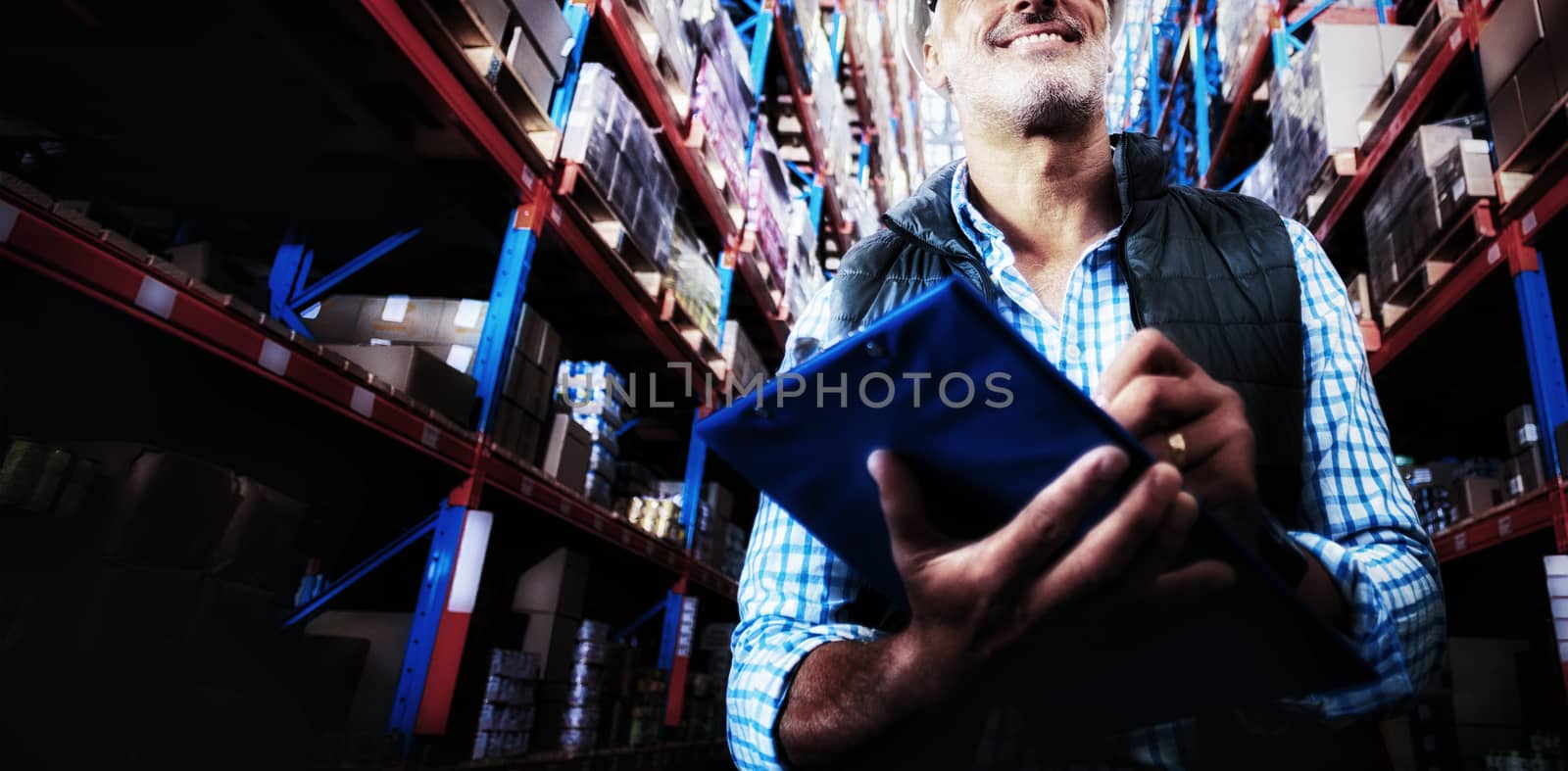 Low angle view of worker is smiling and holding a clipboard in a warehouse