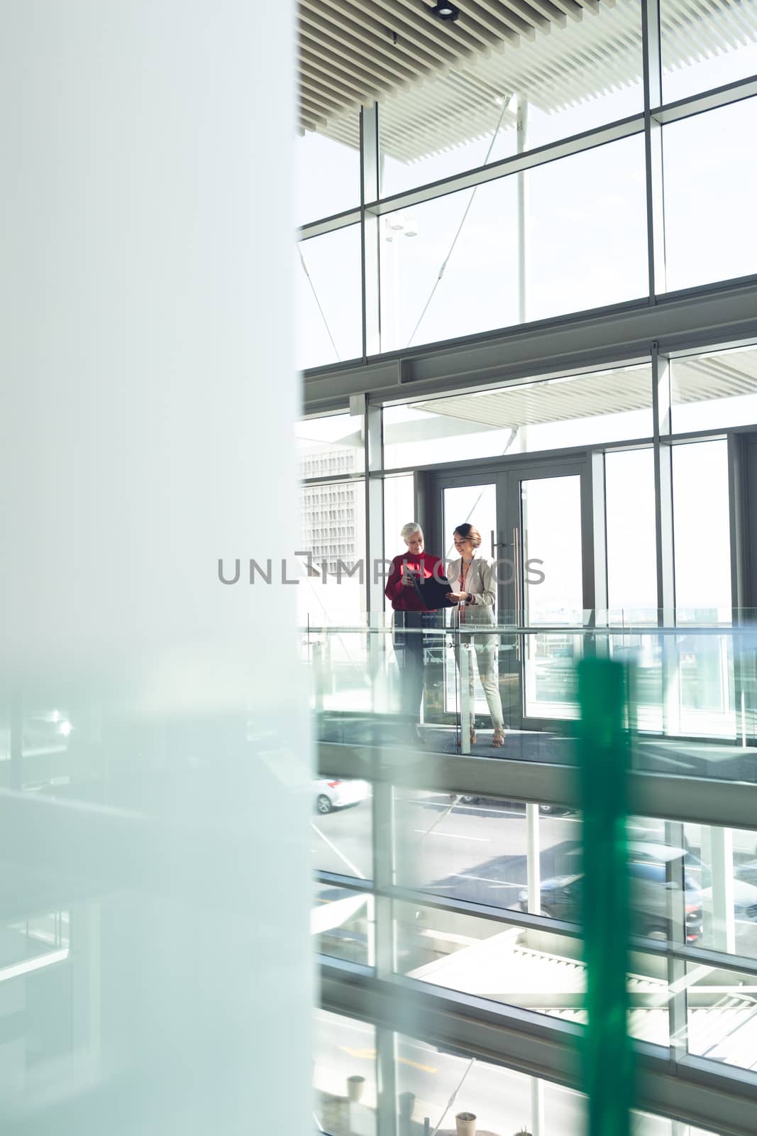 Front view of mixed race businesswomen discussing over laptop in modern office building