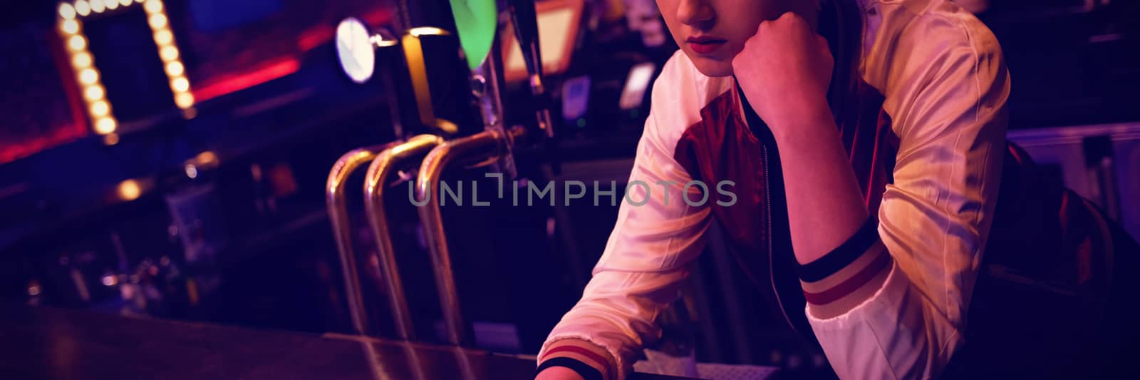 Female bartender using digital tablet while maintaining records at the counter in bar