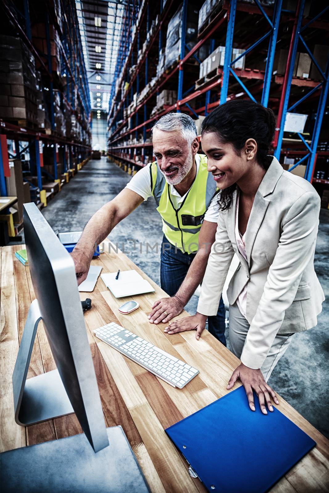 Side view of worker team is looking a computer and smiling in a warehouse