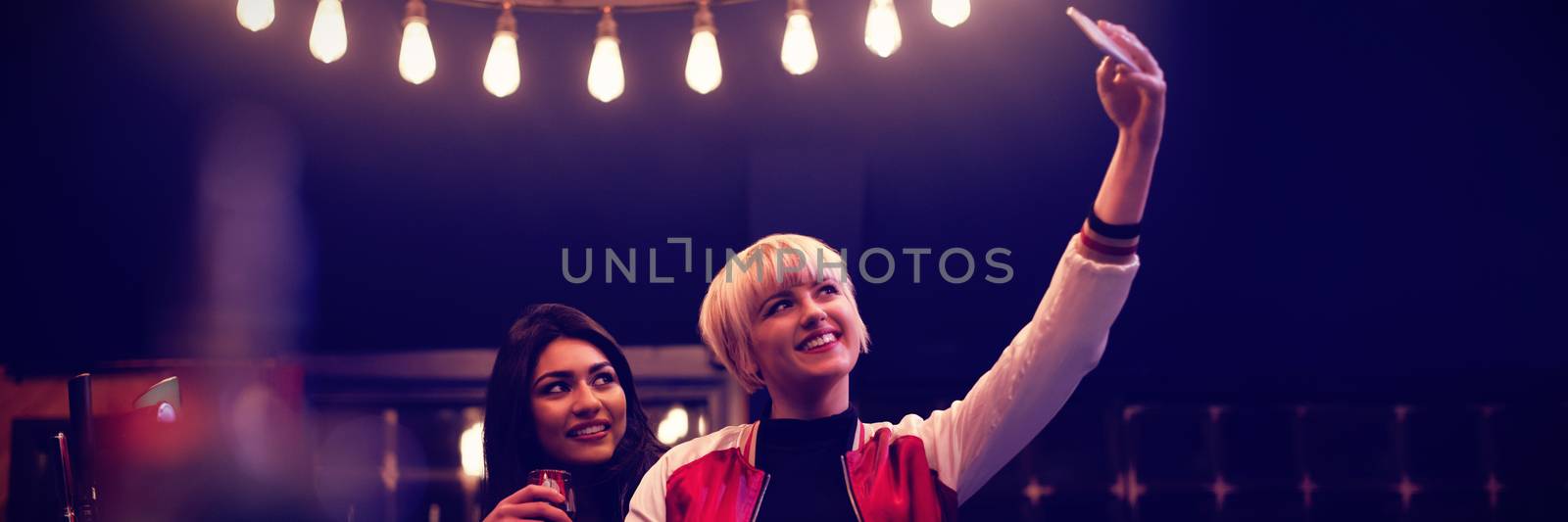 Smiling friends taking a selfie while having wine by Wavebreakmedia