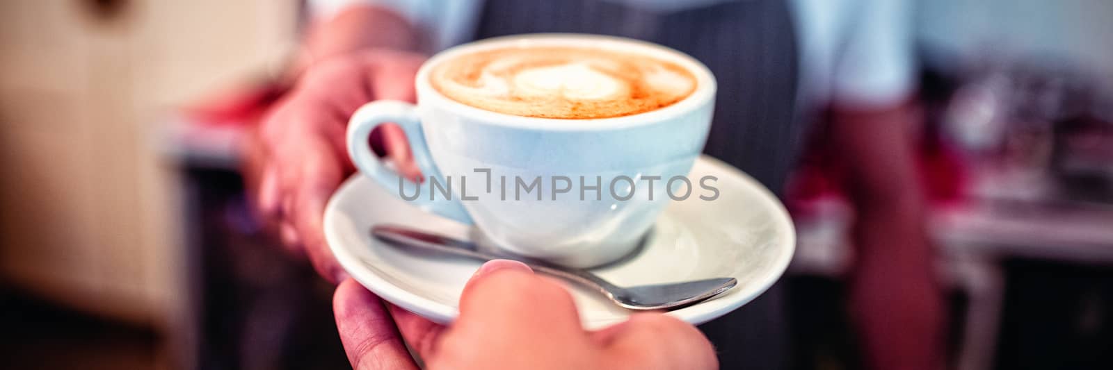 Cropped image of customer taking coffee from waiter at cafe by Wavebreakmedia