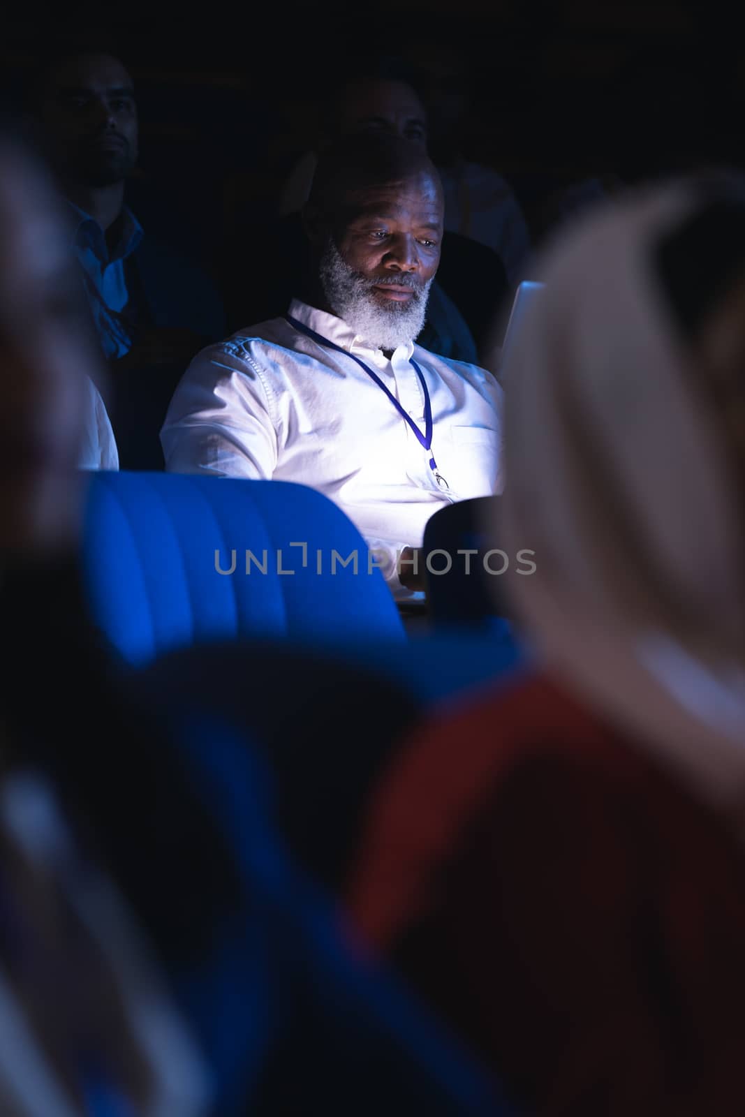 Businessman looking at digital tablet while sitting in the auditorium  by Wavebreakmedia