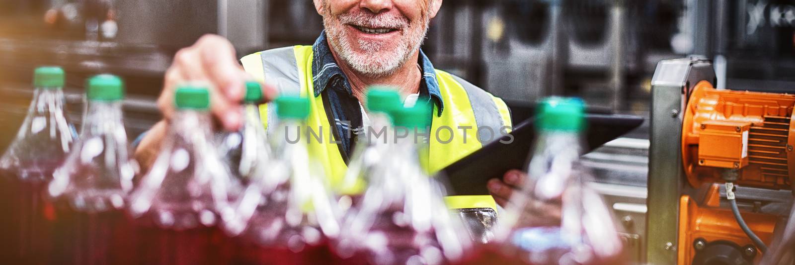Portrait of male factory worker monitoring cold drink bottles at drinks production factory
