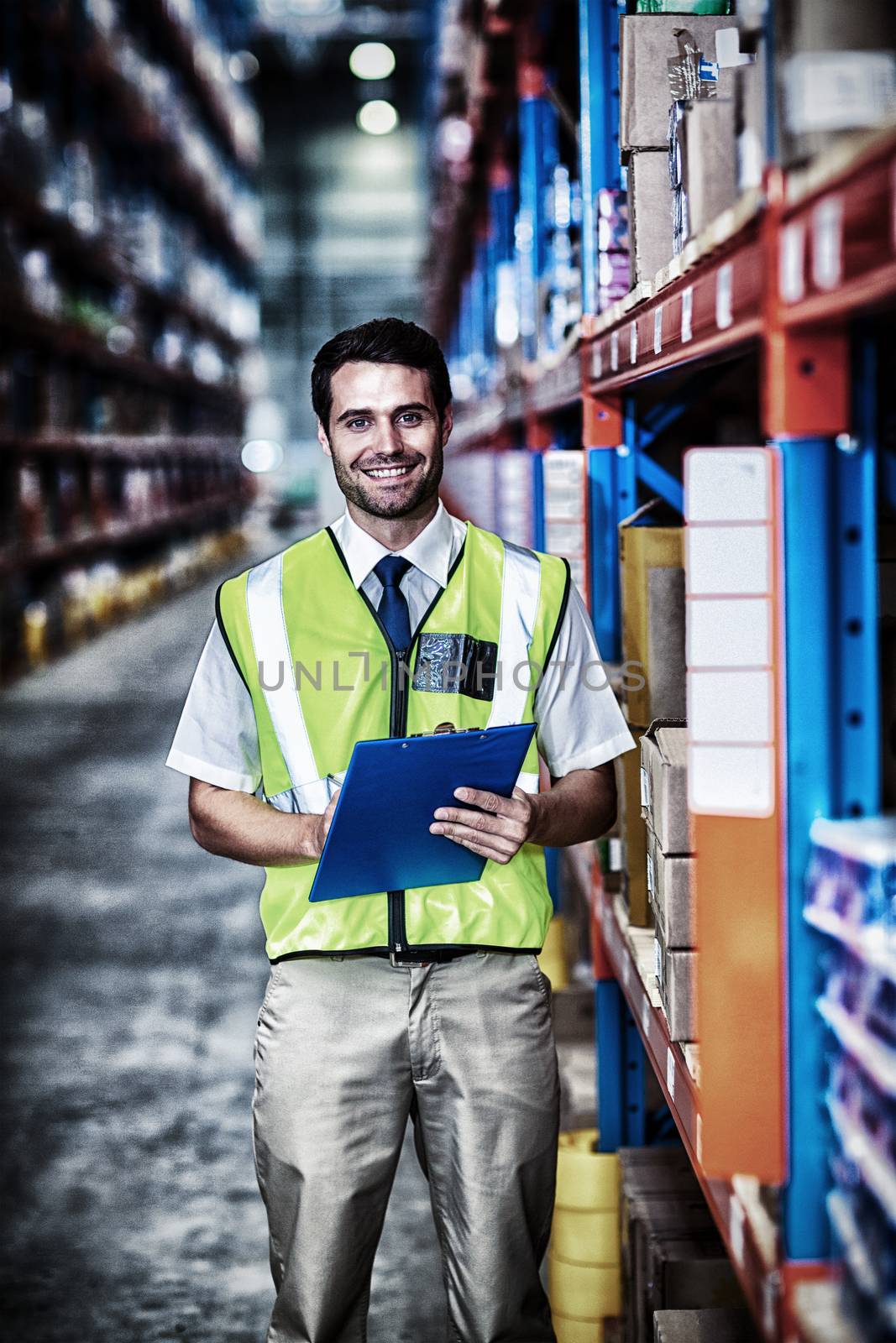 Worker with clipboard looking at camera in warehouse