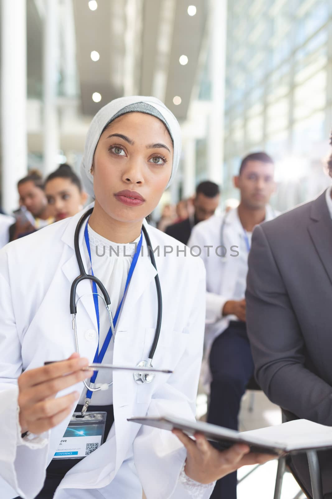 Front view of mixed race  female doctor with notebook and pen attending seminar in conference room