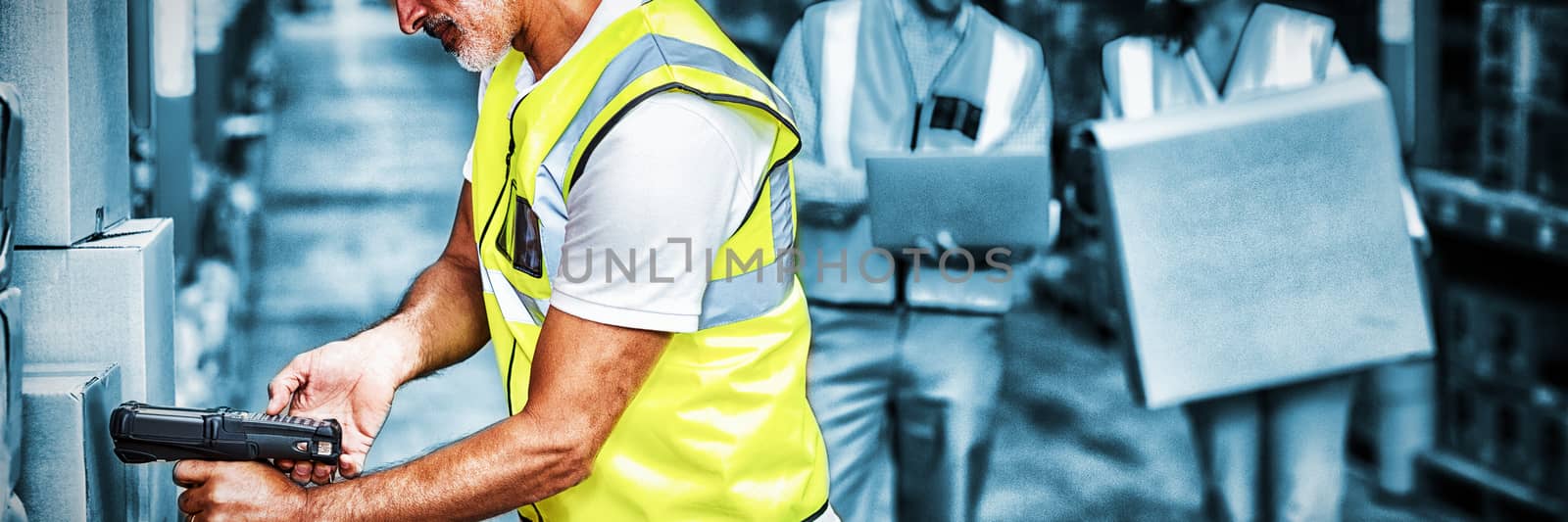 Worker is working on cardboard boxes with his colleagues by Wavebreakmedia