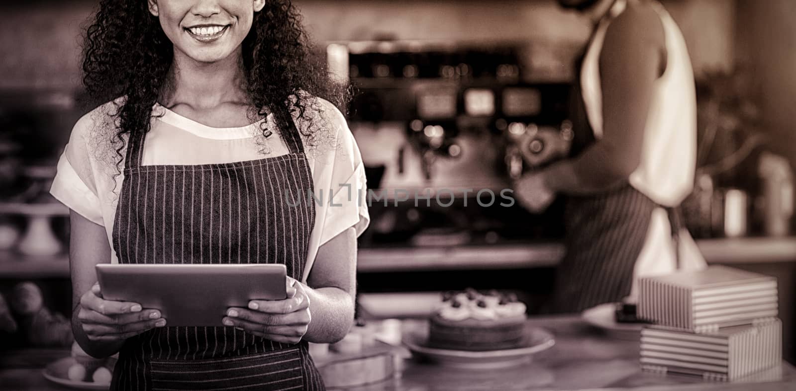 Portrait of smiling waitress using digital tablet at counter in cafÃ©