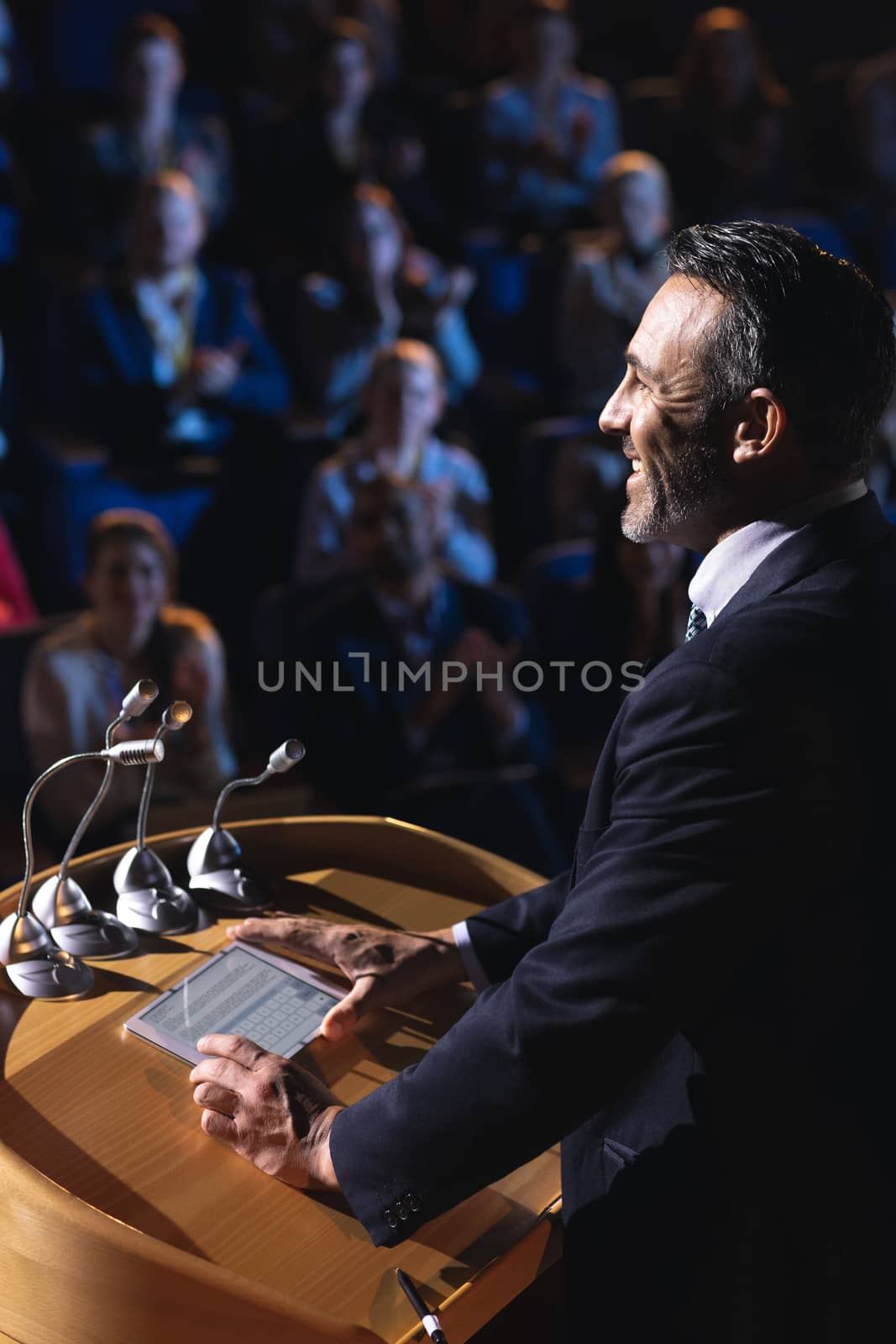 Side view of Caucasian businessman standing and giving presentation in the auditorium 