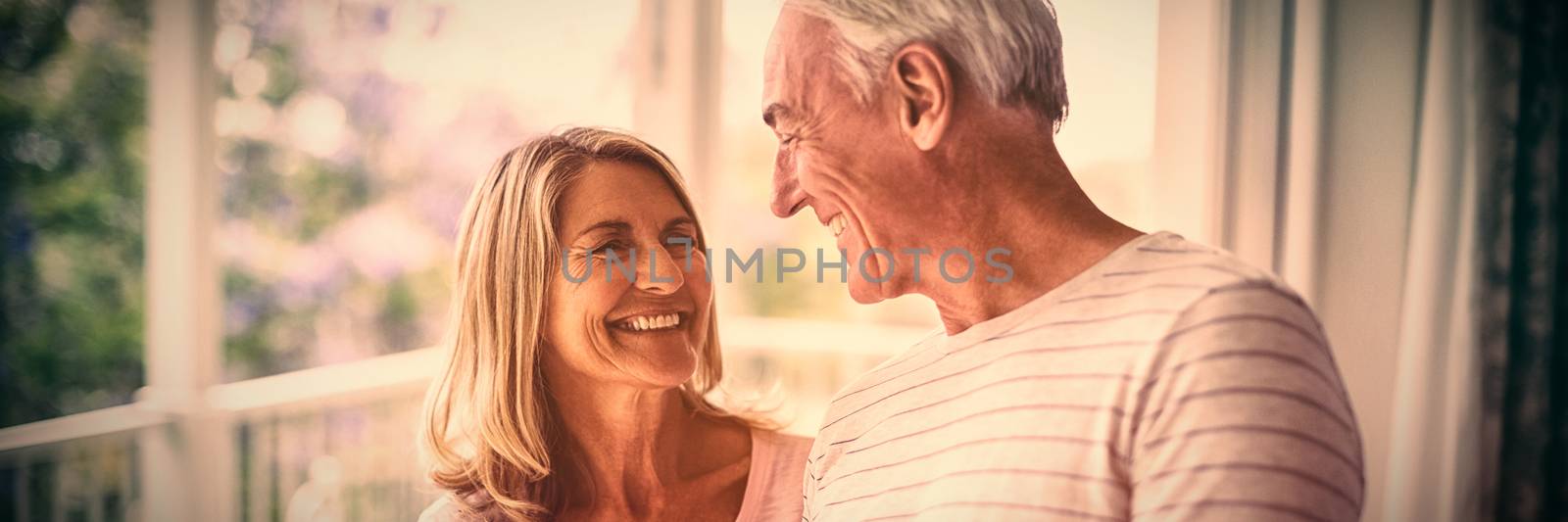 Happy senior couple interacting with each other in balcony at home