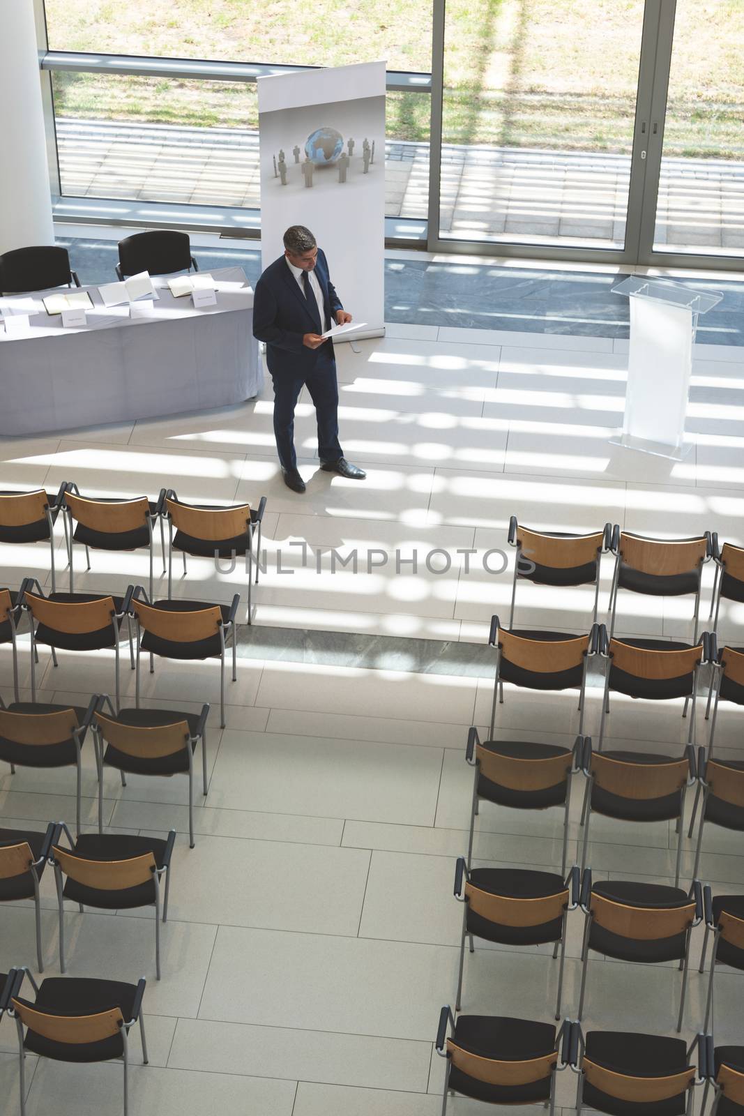 High angle view of mixed race businessman practising speech in empty conference room in modern office building