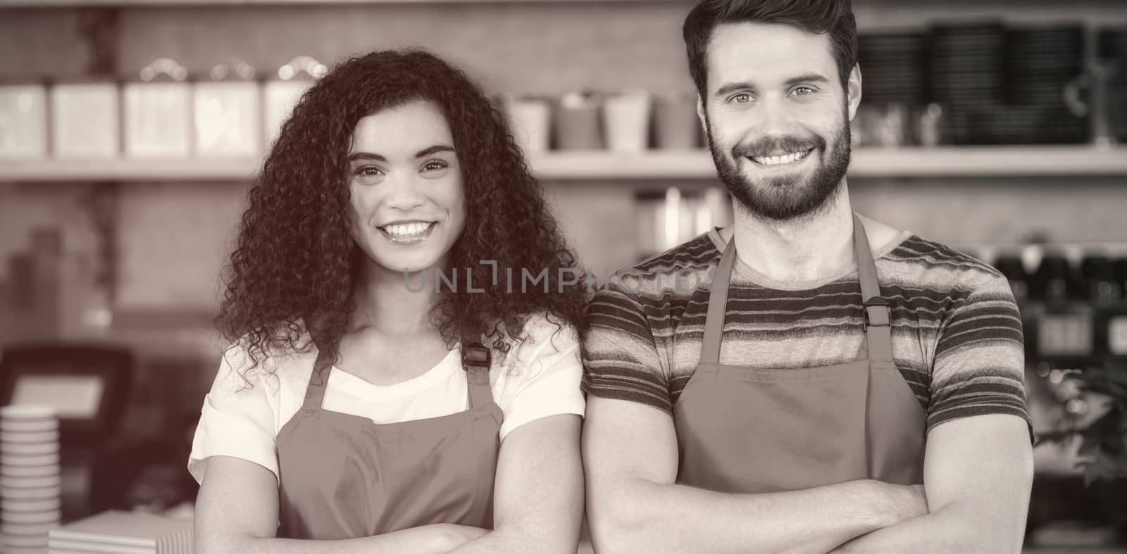 Portrait of smiling waiter and waitress standing at counter in cafe