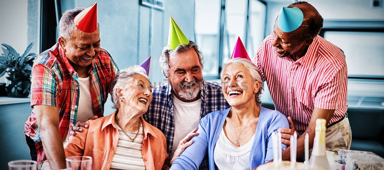 Cheerful friends looking at excited senior woman during birthday party in nursing home