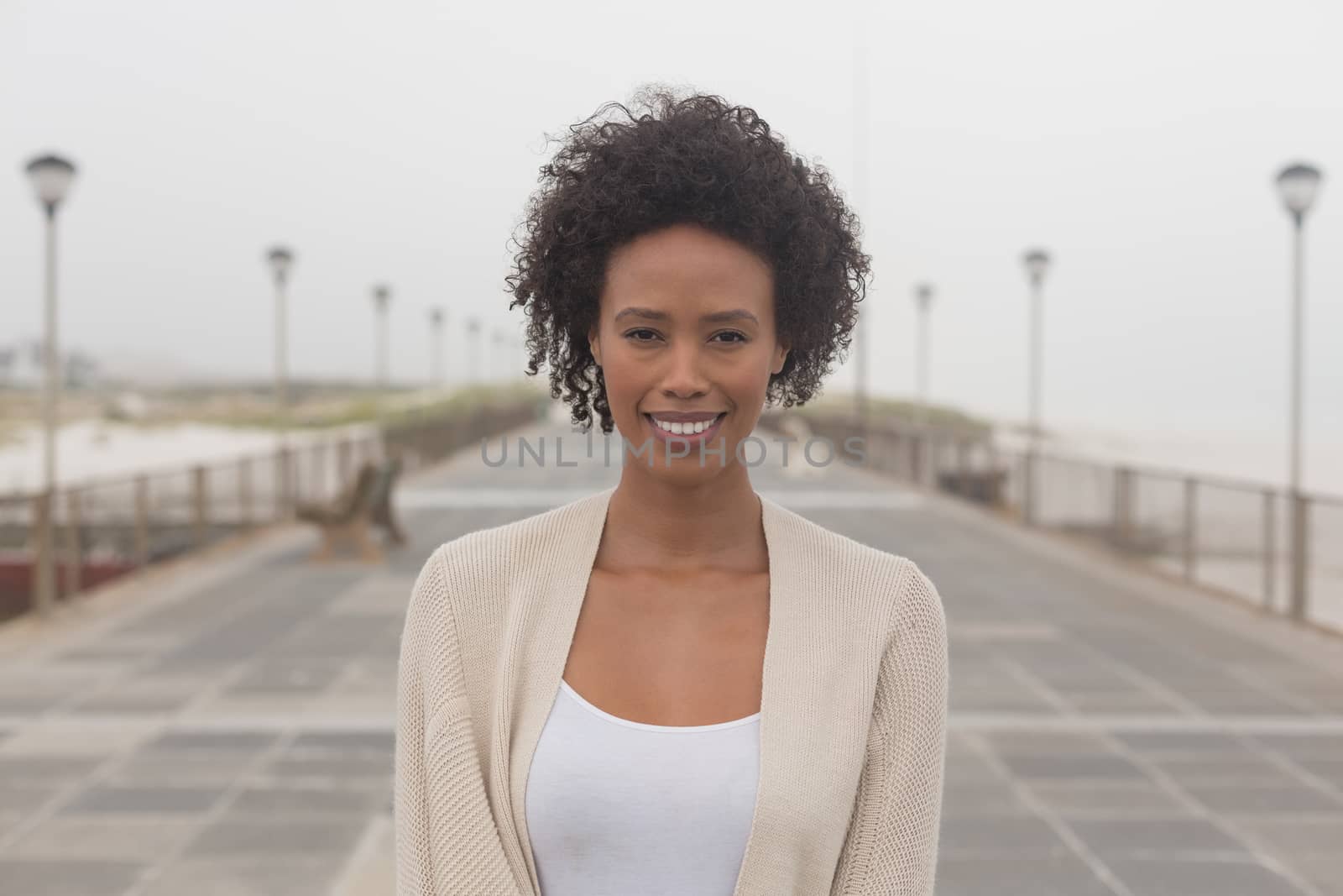 Portrait of happy young African American woman looking at camera on promenade. She is smiling