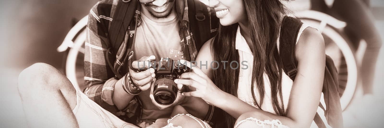 Happy young couple sitting on road looking in camera