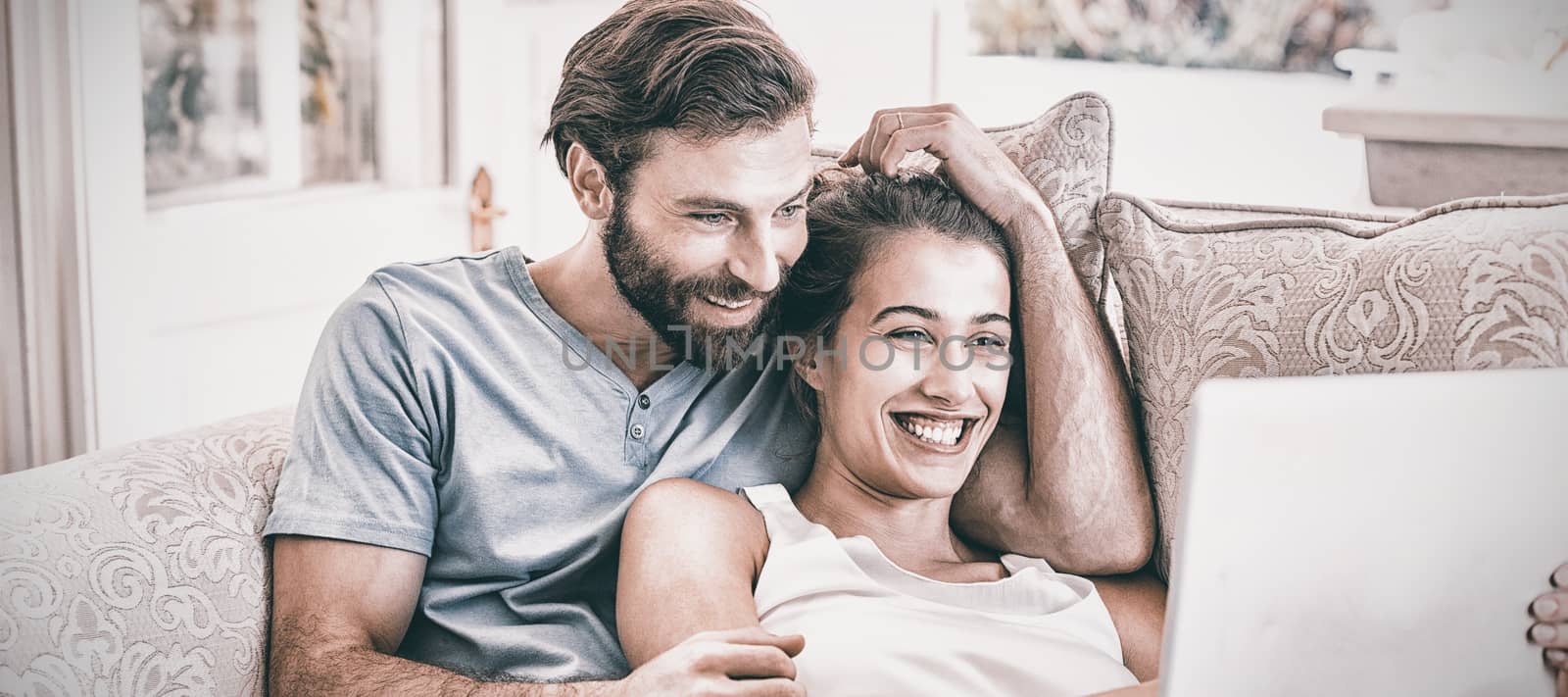 Couple sitting on sofa and using laptop at home