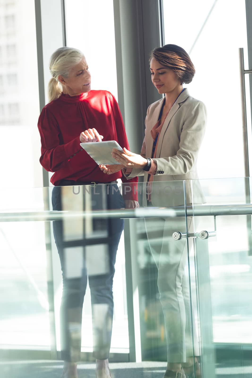 Businesswomen discussing over digital tablet in office building by Wavebreakmedia