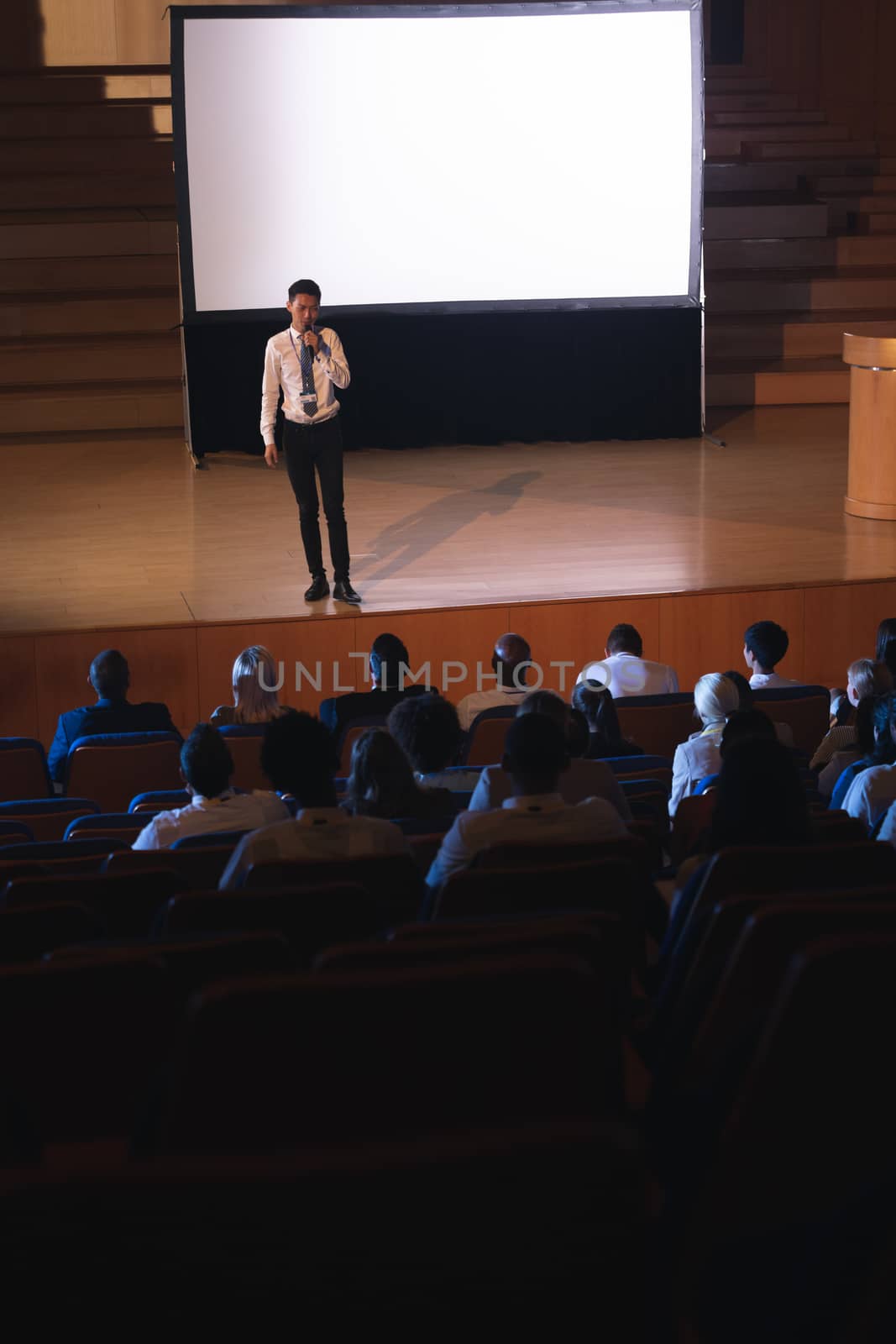 Businessman standing and giving presentation in auditorium  by Wavebreakmedia