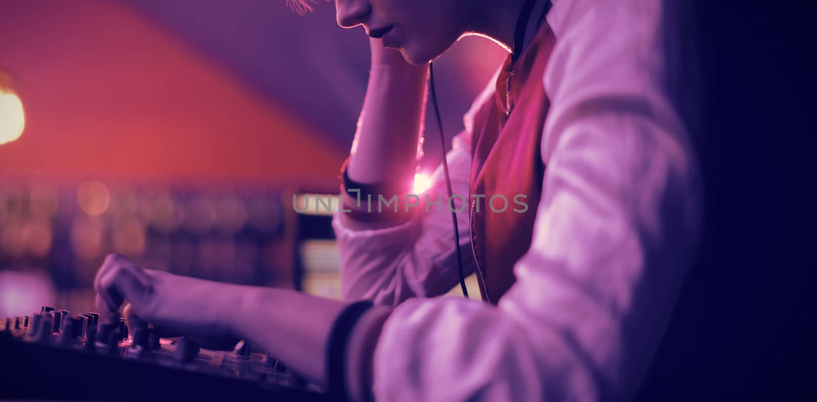 Female dj listening to headphones while playing music in bar