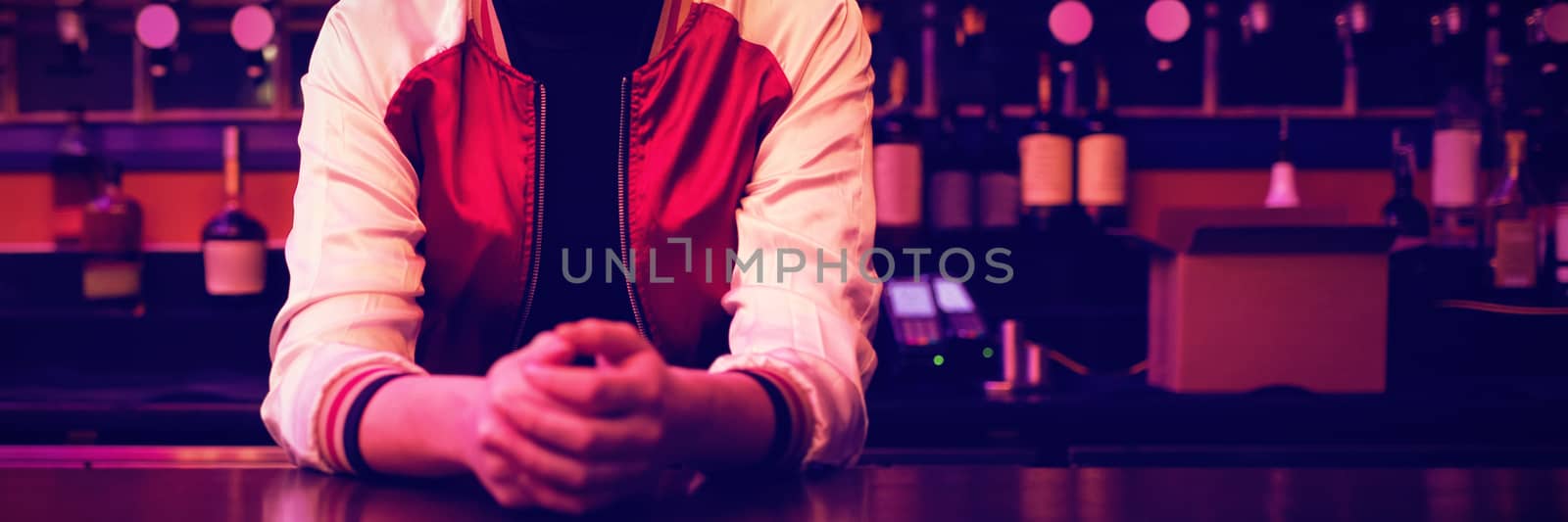 Female bartender standing at bar counter by Wavebreakmedia