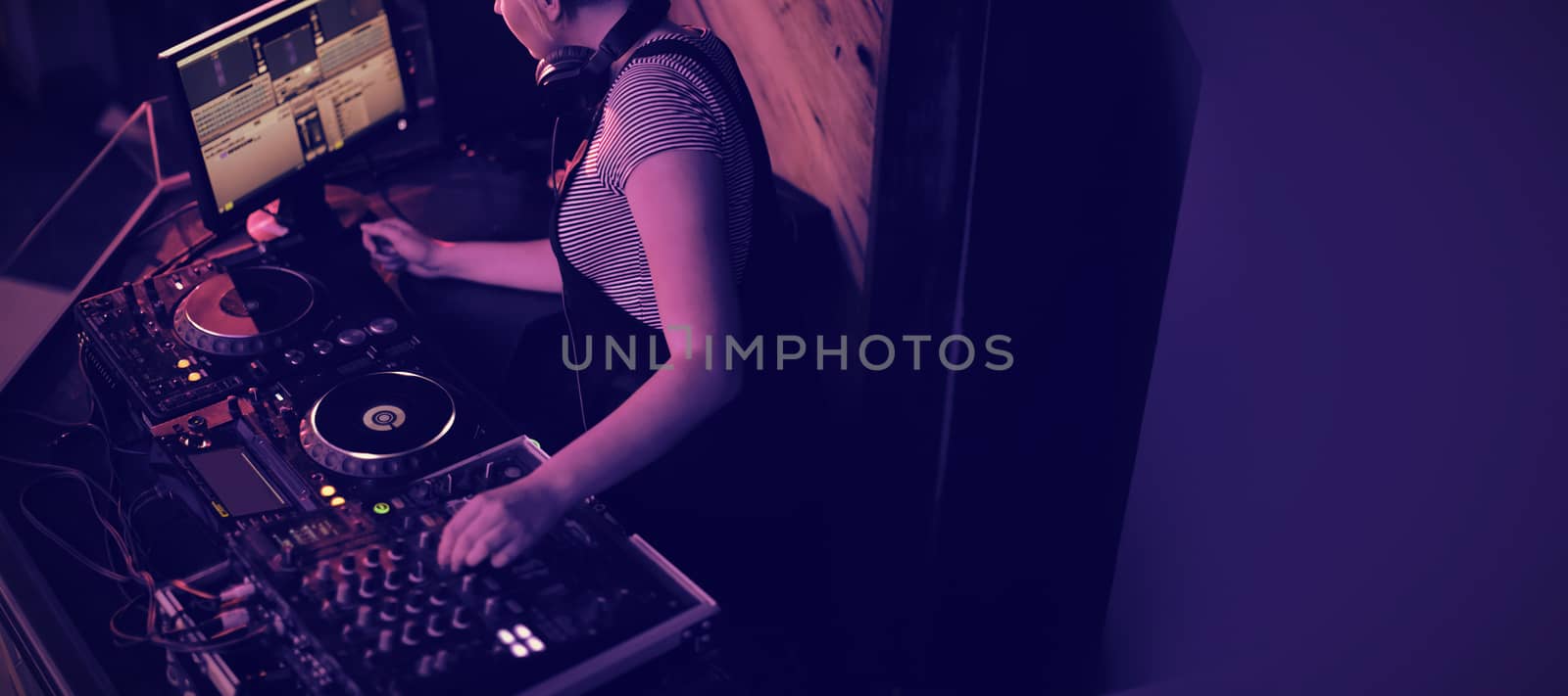 Female dj mixing music on mixing console in bar