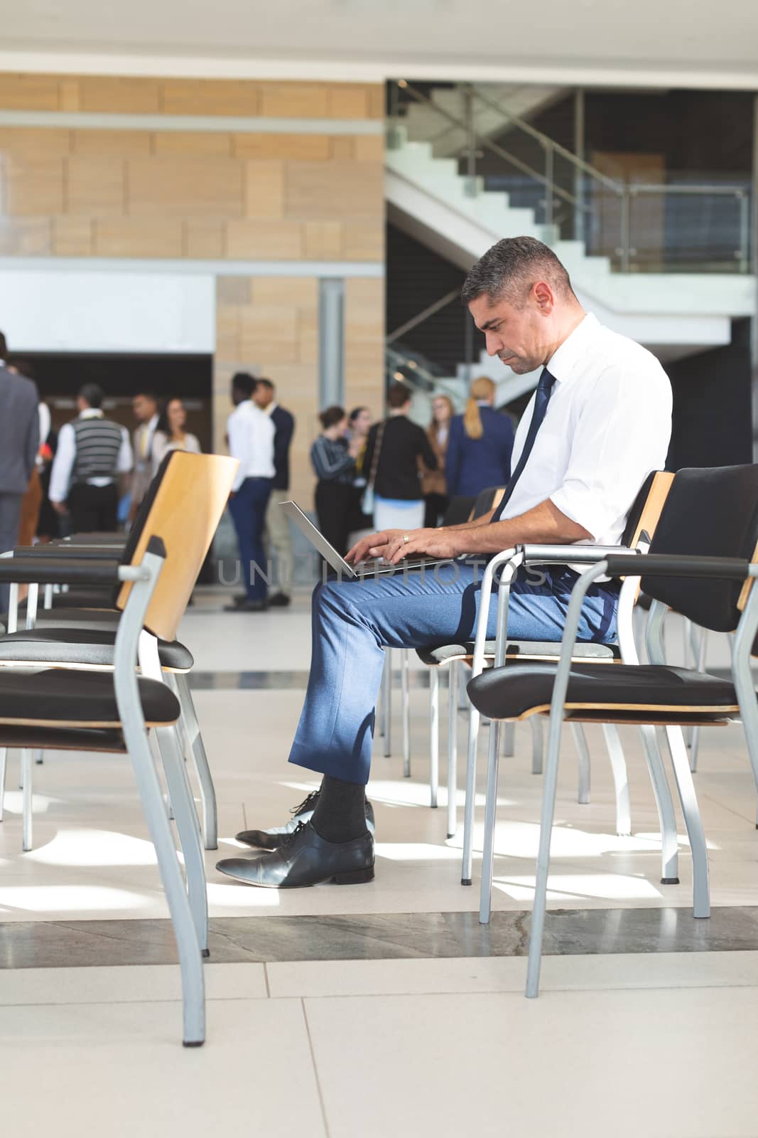 Side view of Caucasian businessman sitting on chair and using laptop in conference room at office