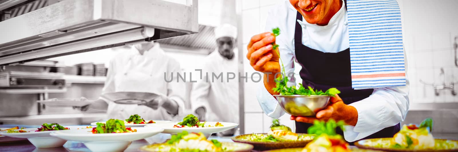 Happy chef garnishing appetizer plates at order station in restaurant