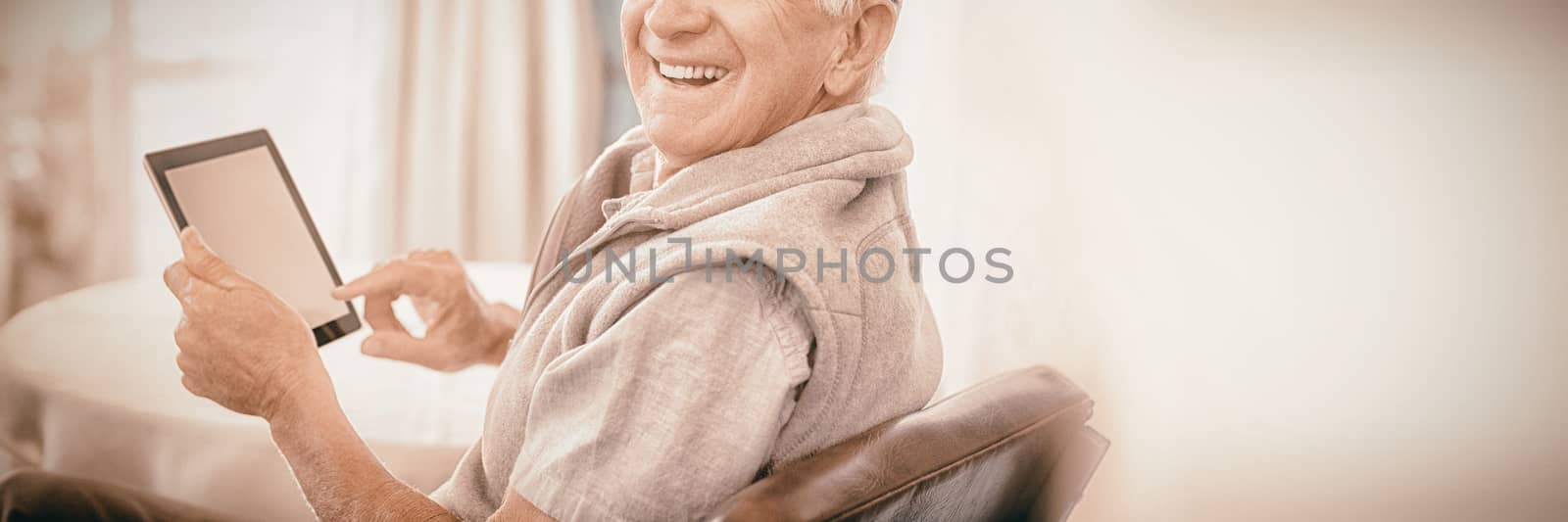Portrait of senior man using digital tablet while sitting at home