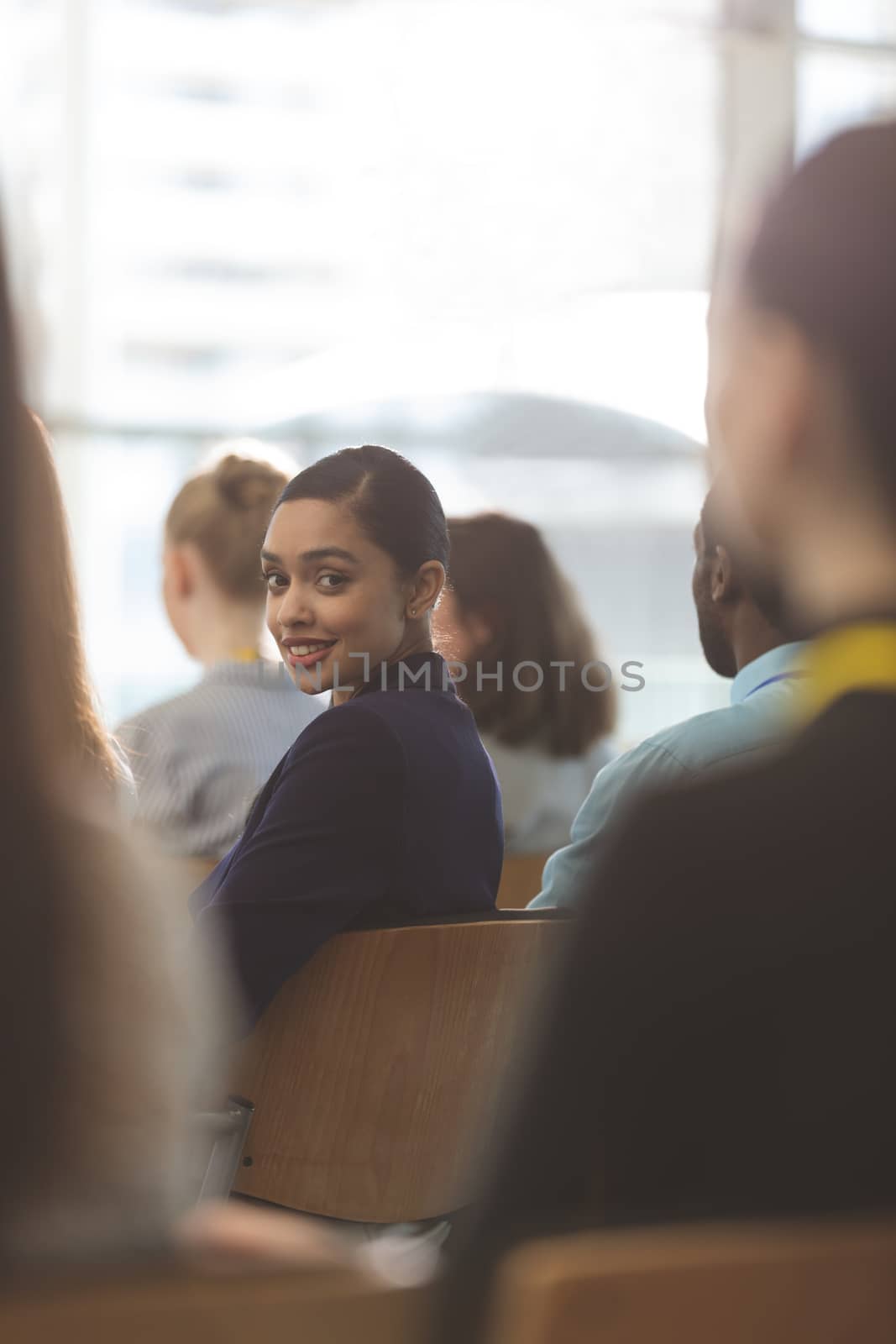 Portrait of beautiful young mixed race businesswoman looking at camera during seminar in office building