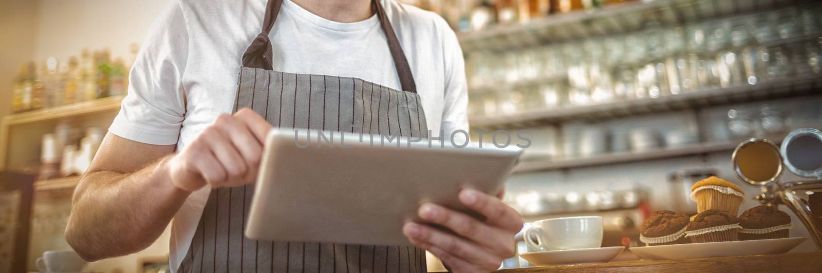 Happy male barista using digital tablet at cafe