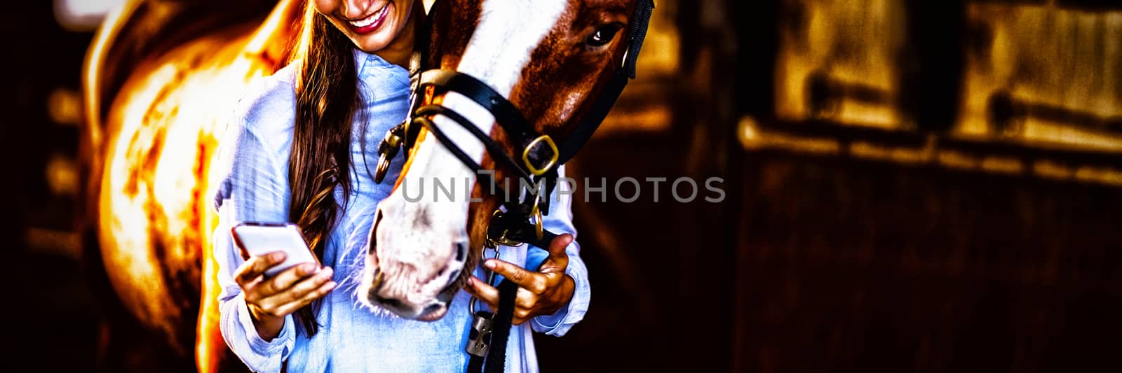 Female vet using mobile phone while standing by horse in stable