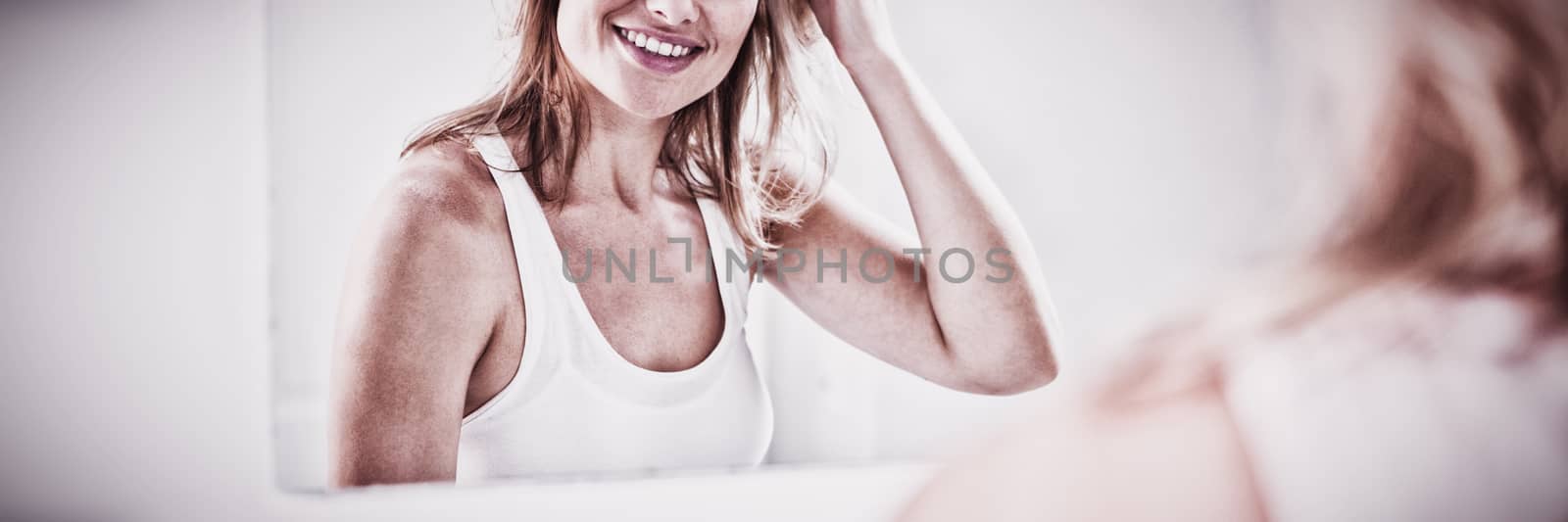 Young woman checking her hair in bathroom mirror by Wavebreakmedia