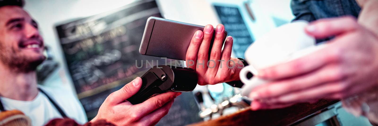 Customer with cellphone standing with barista at cafe by Wavebreakmedia