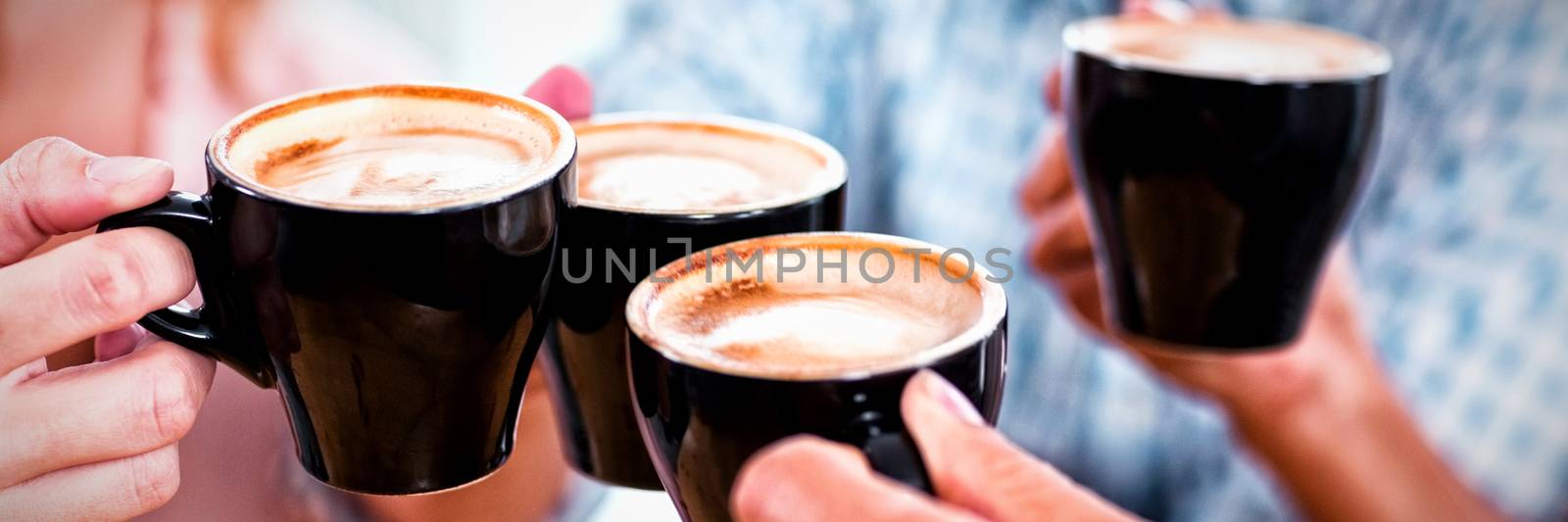 Group of happy friends toasting cup of coffee in cafe