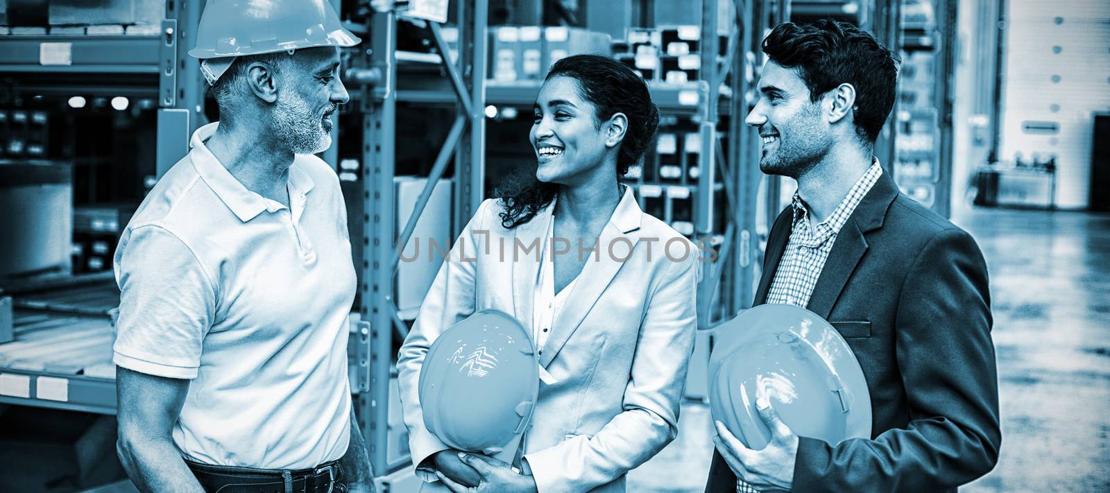 Happy warehouse managers and worker standing together in warehouse office