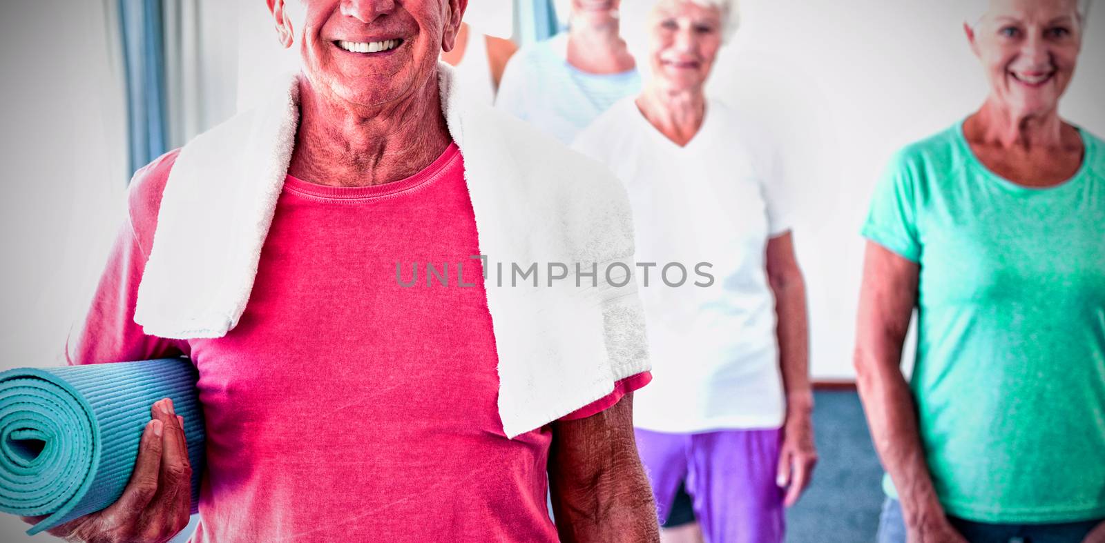 Senior man holding yoga mat during yoga class