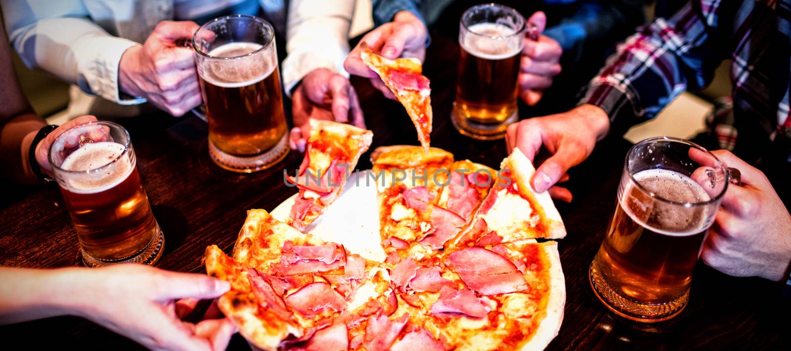 High angle view of friends with beer mug and pizza on table in bar