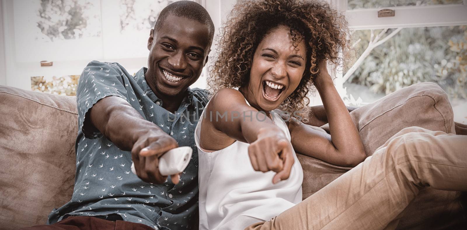 Happy young couple watching television by Wavebreakmedia