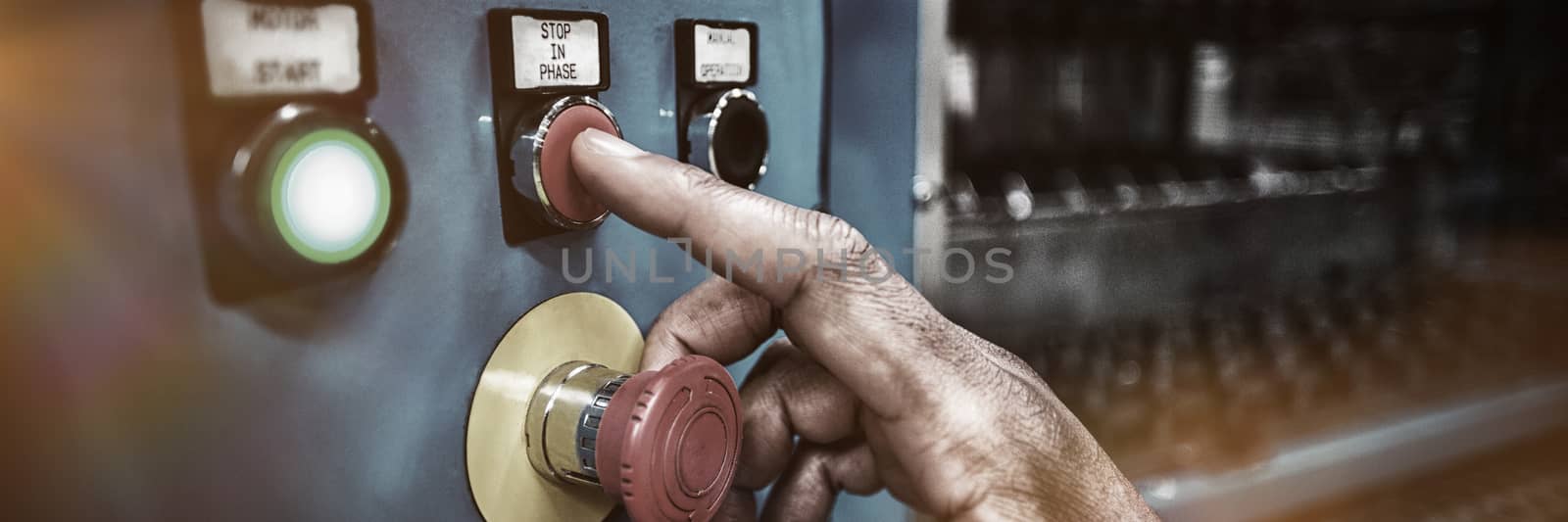 Hands of factory worker pressing a red button on the control board in factory