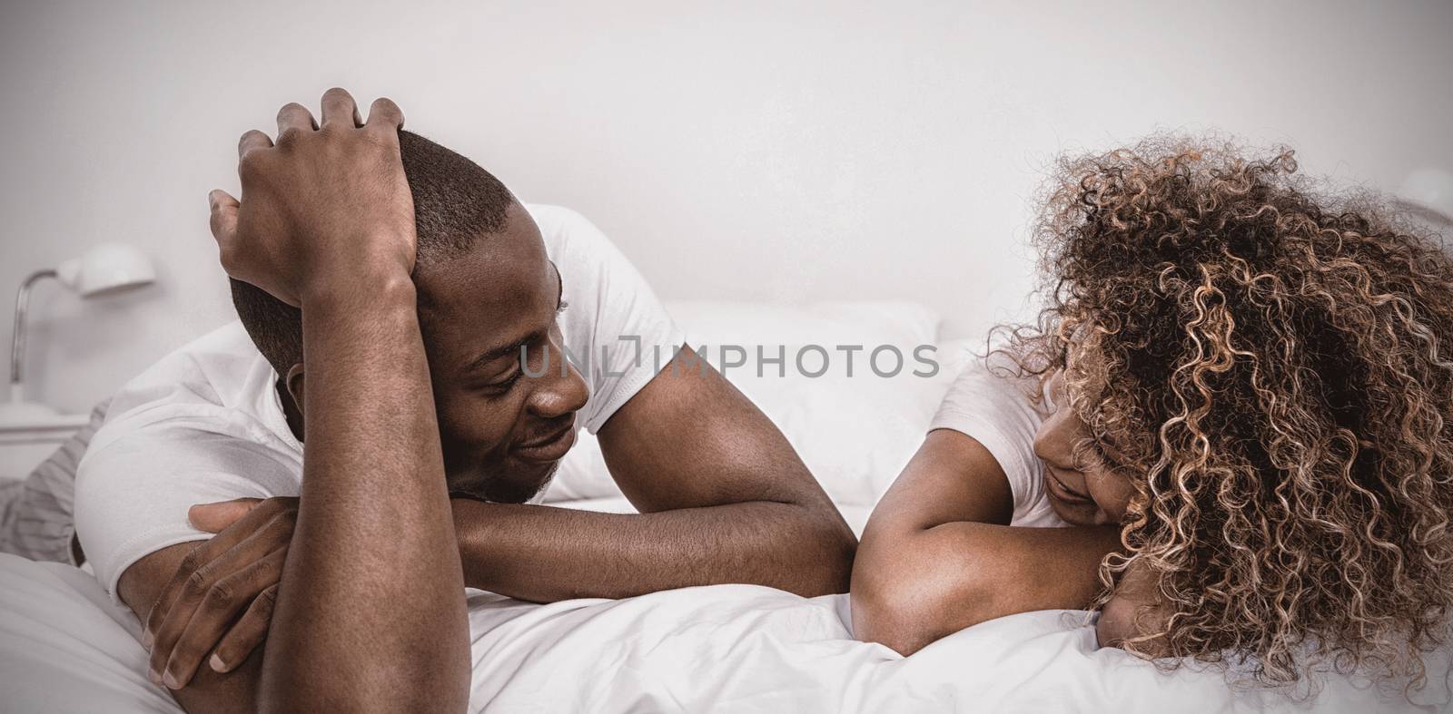 Young couple lying on bed and talking in bedroom