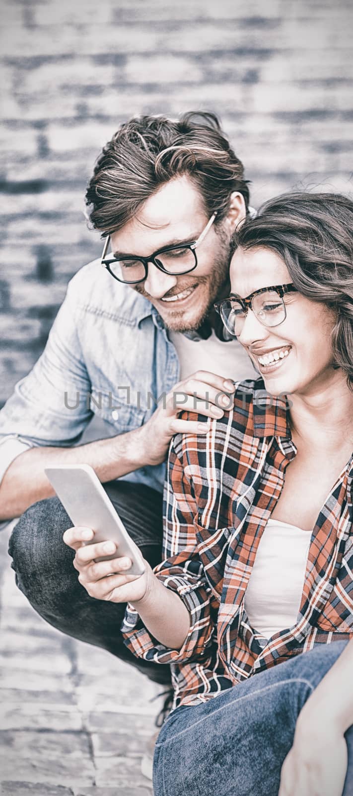 Happy young couple in spectacles using mobile phone
